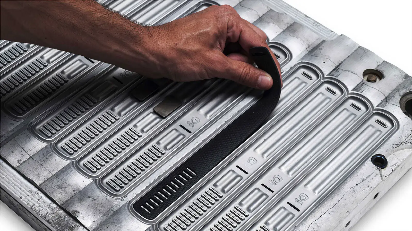 Hand lifting a molded strap out of a machined aluminum mold