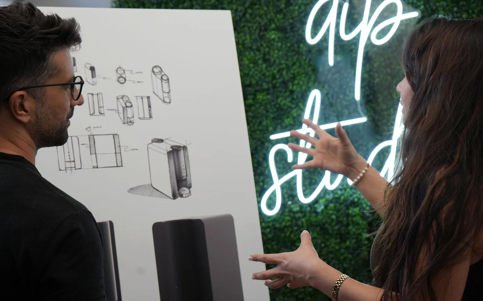 Two Dip Studio designers reviewing product sketches on a whiteboard in the studio