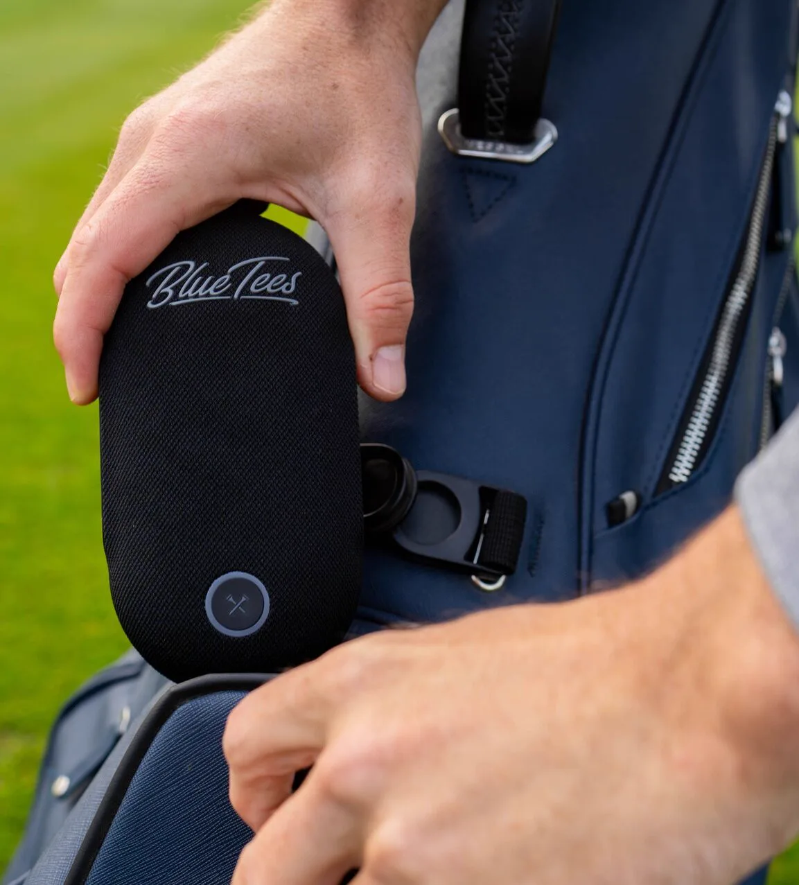 PlayerGo clipped to a golf bag, held in a hand