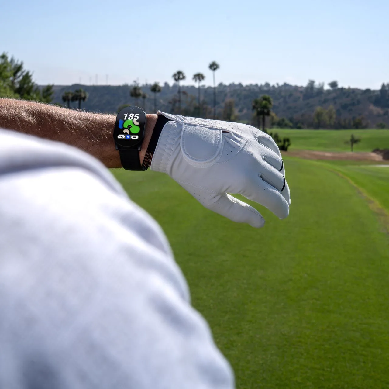 PlayMaker+ on a golfer's wrist with the fairway ahead