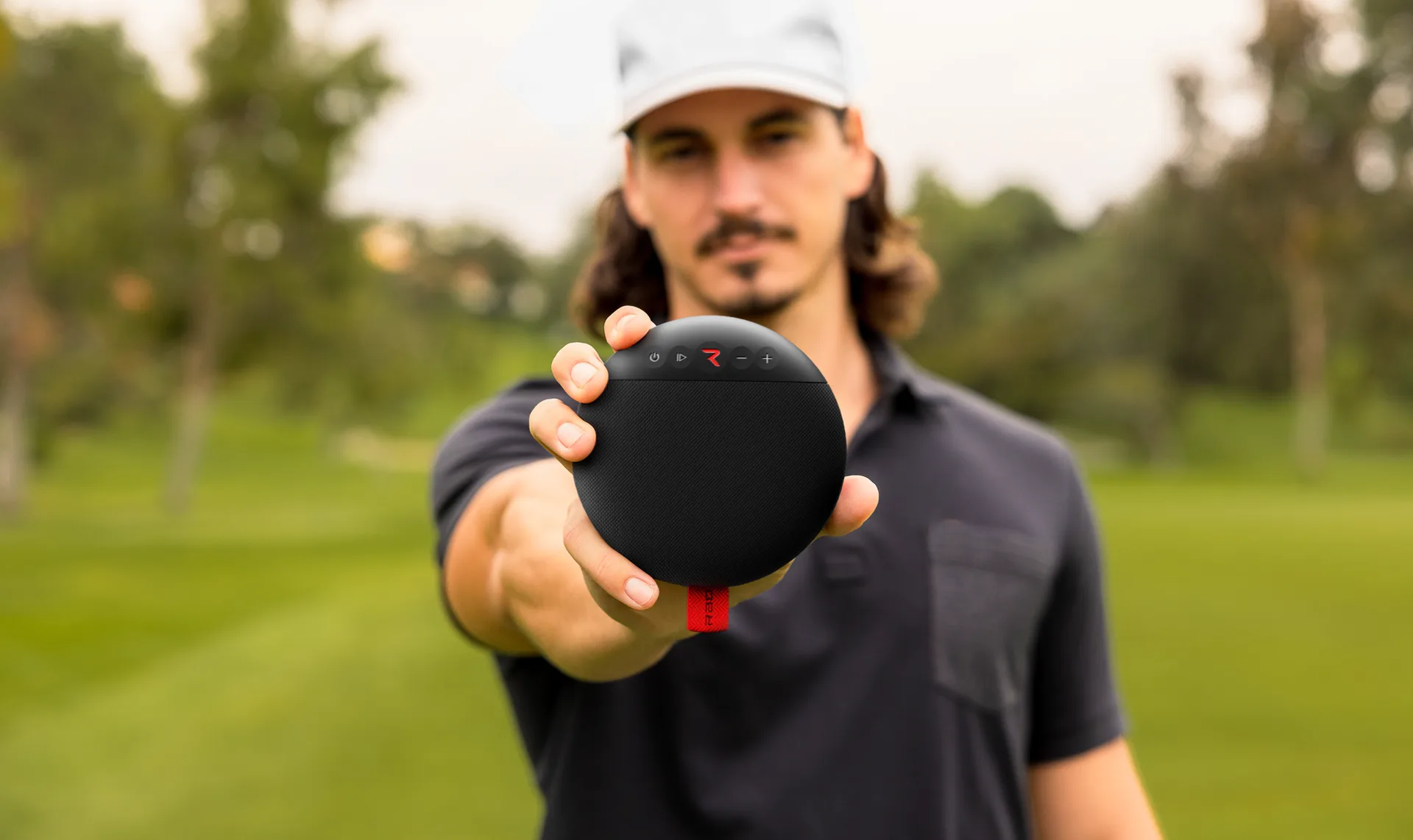 Golfer holding the Rad Sound speaker toward the camera