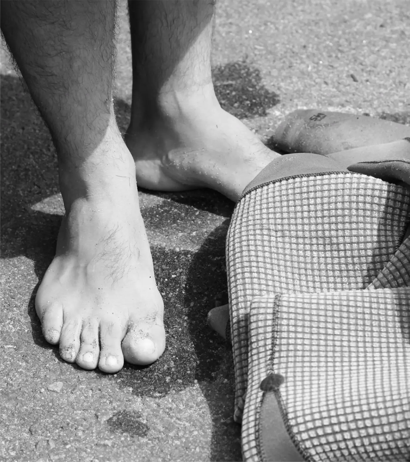 Bare feet on wet asphalt next to the SAAL Surfbag changing mat
