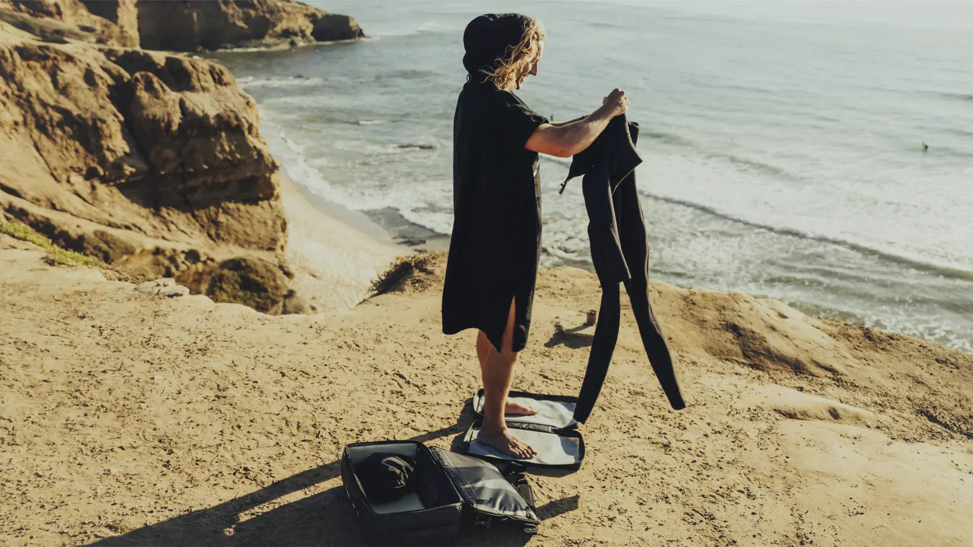 Surfer changing on the SAAL Surfbag mat at the beach