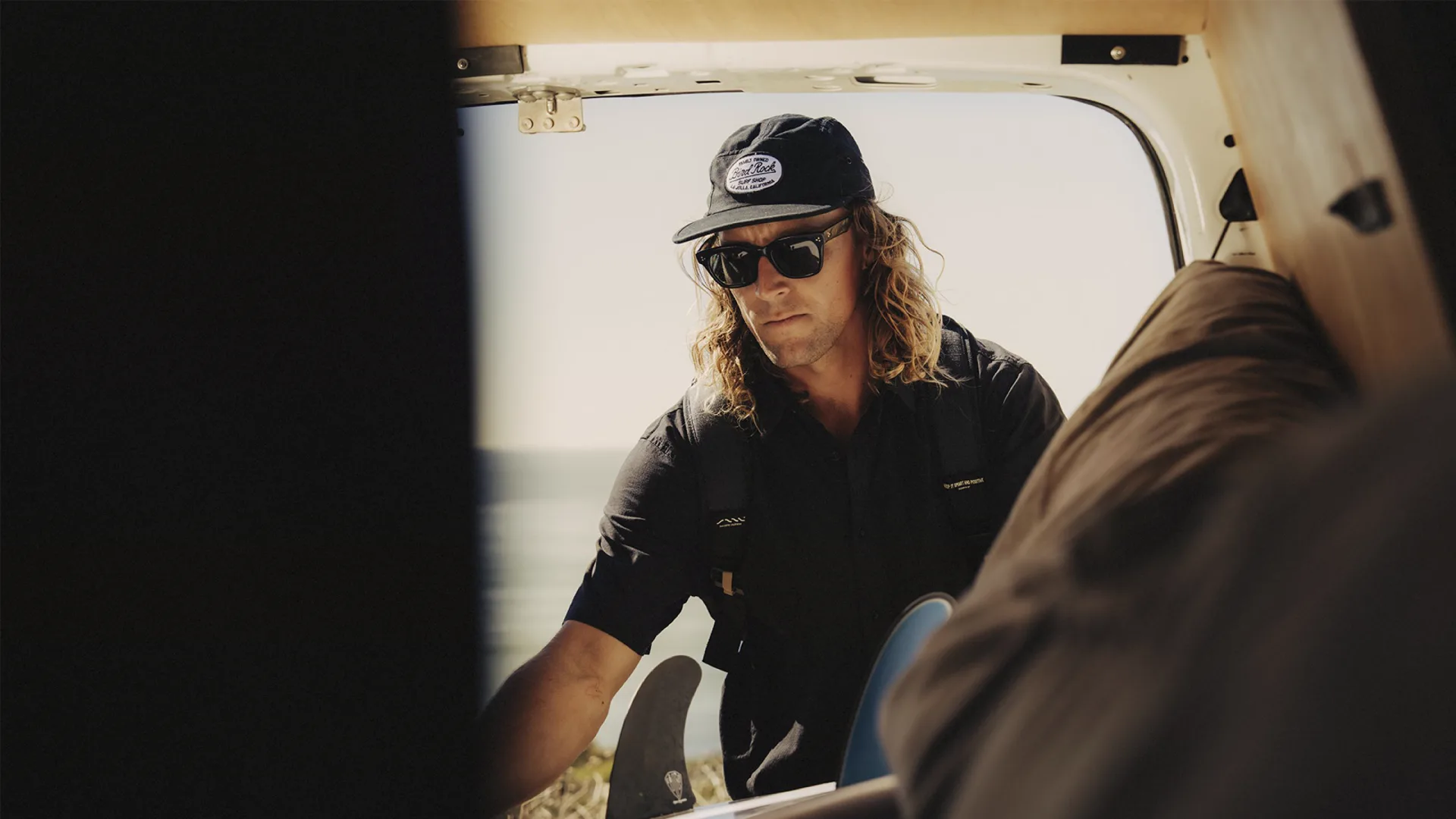 Surfer sitting in a van, presentation still