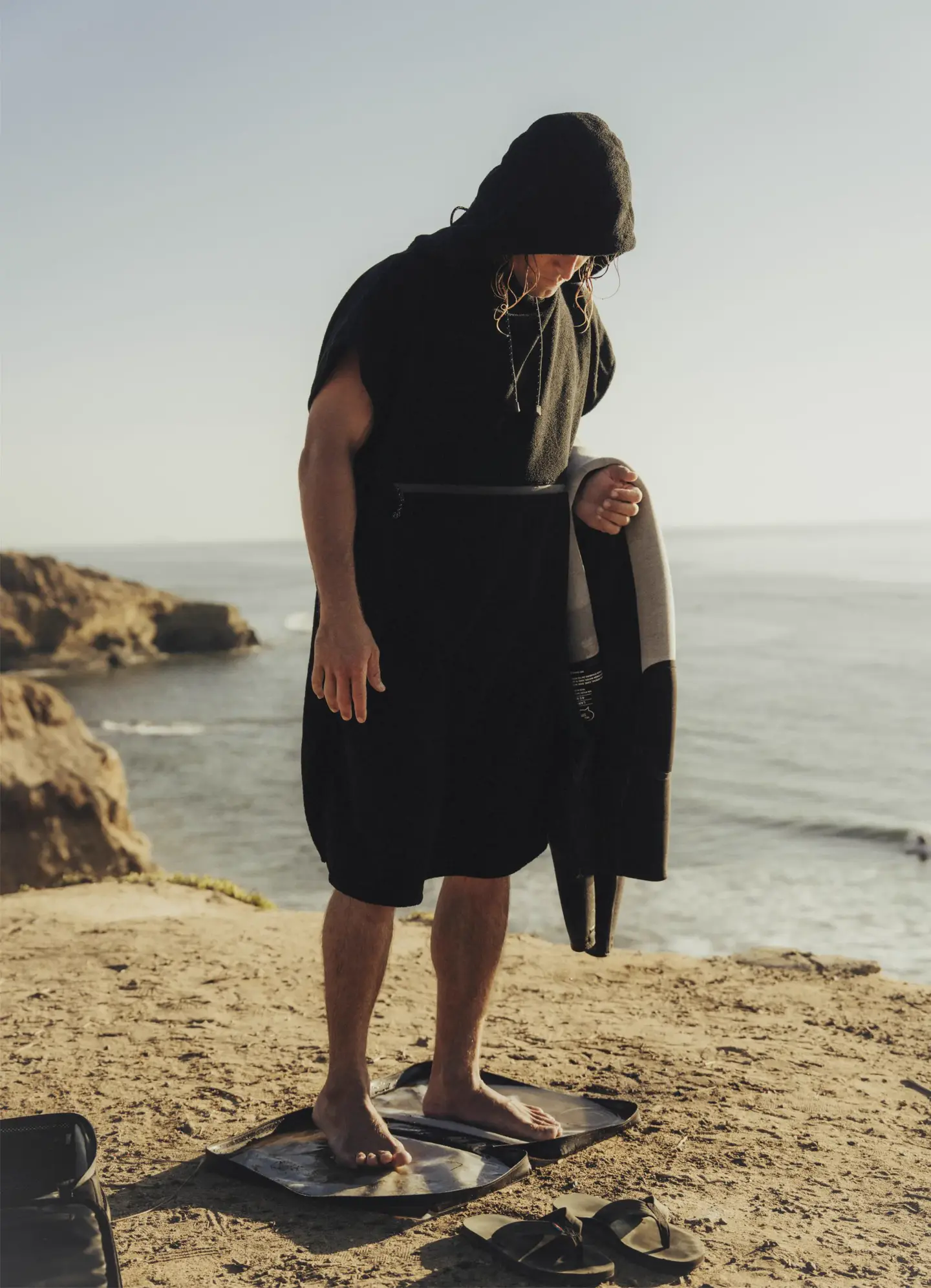Surfer standing on the SAAL Surfbag changing mat by the ocean
