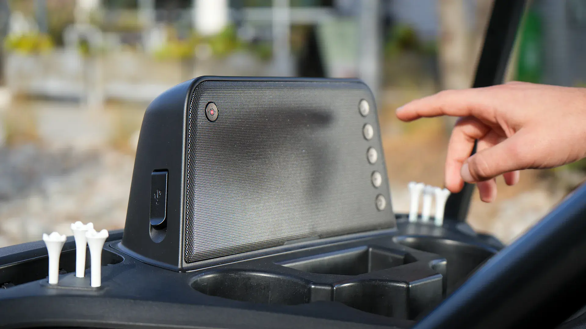 Hand pressing a button on the Yamaha in-dash speaker in a golf cart